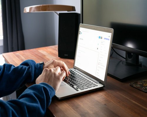 Person working on a laptop at a bright wooden desk