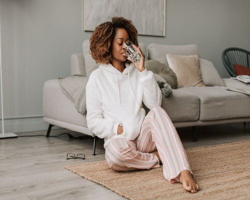 Woman drinking water while sitting on a cozy sofa in the morning